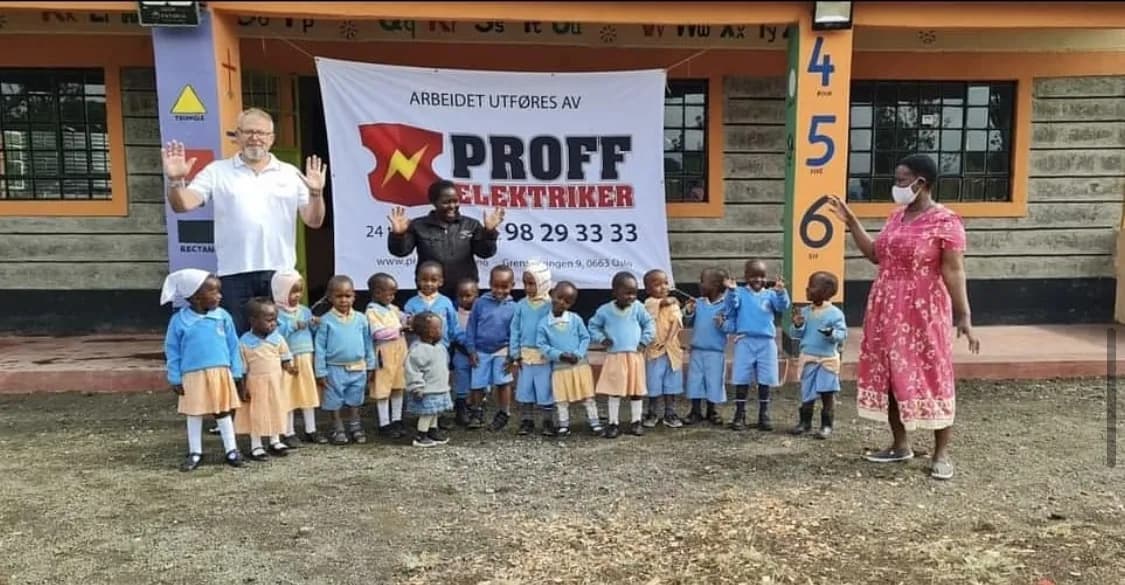 Skolebarn foran et banner fra Proff Elektriker